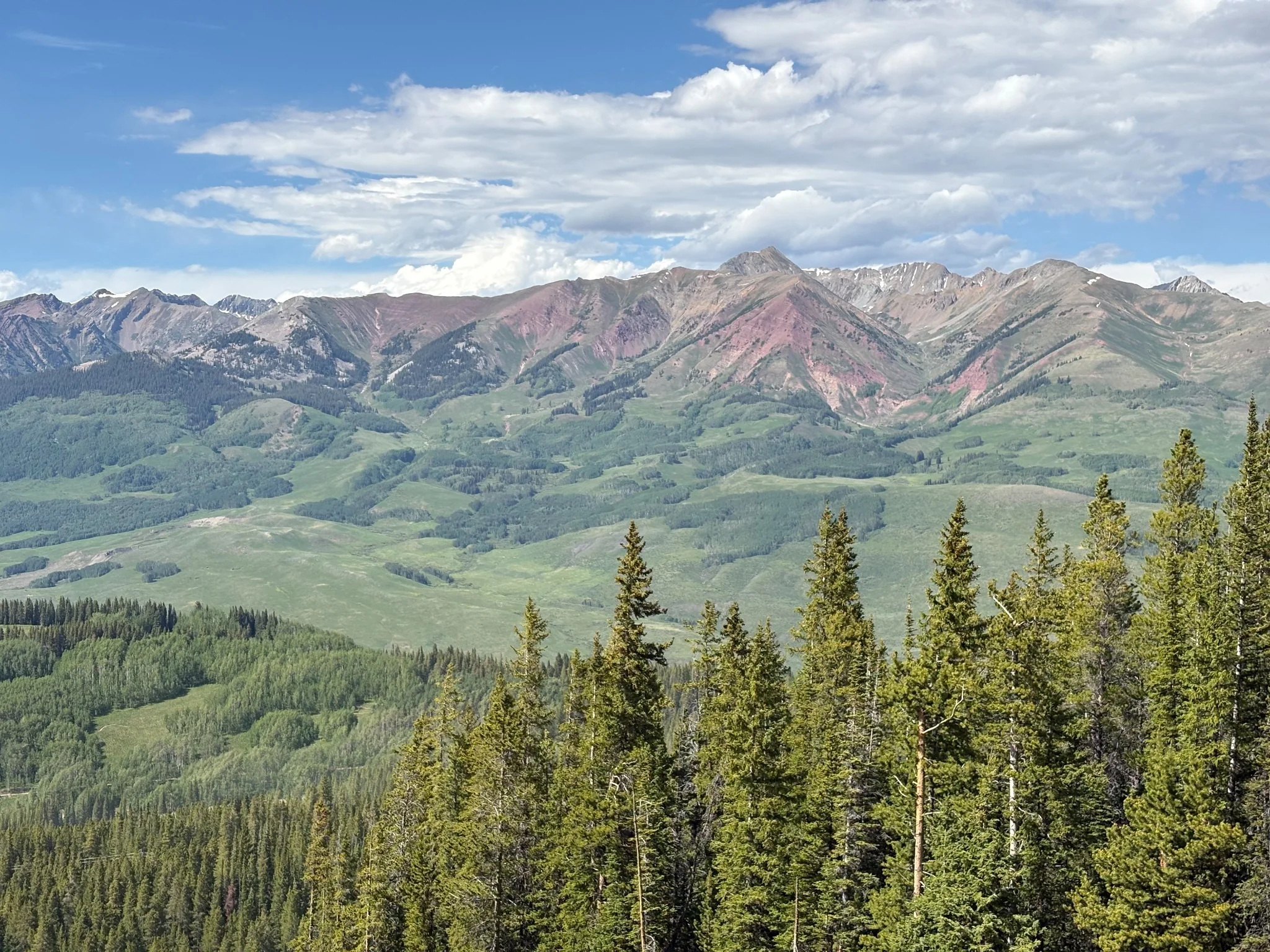 Broad green slopes and striking rocky ridgeline under a summer sky